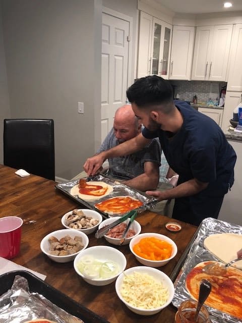 Two people making homemade pizzas together in the kitchen.