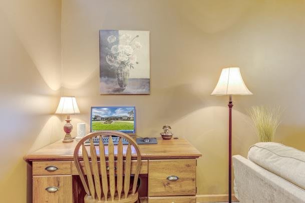 Cozy home office setup with a wooden desk, computer, and warm lighting.