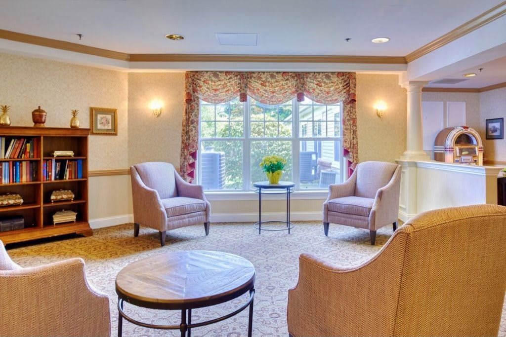 A cozy living room with comfortable chairs, a small table, and a large window.