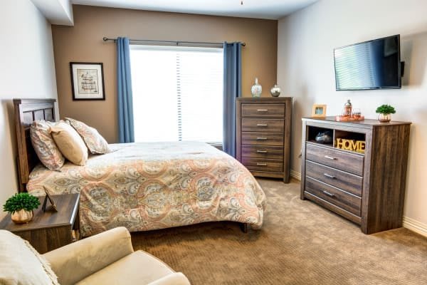 A cozy bedroom with a bed, dresser, and window with blue curtains.