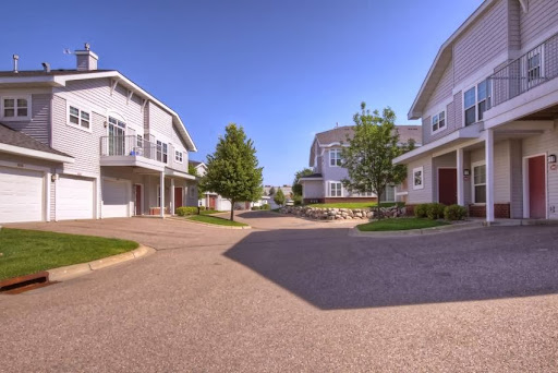 A peaceful residential neighborhood featuring modern homes and well-maintained landscaping under a clear blue sky.