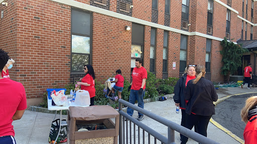 A community gathering featuring individuals in red shirts outside a brick building.