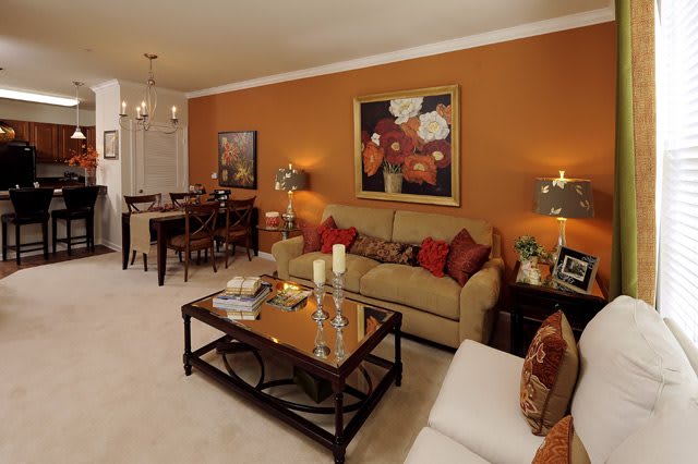 A cozy living room with warm colors, featuring a sofa, coffee table, and adjacent dining area.