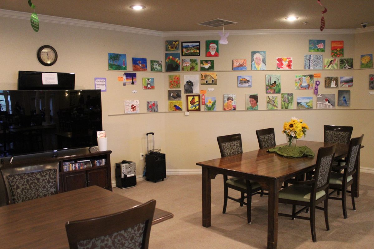 A cozy living room with a dining area and a vibrant display of artwork on the wall.