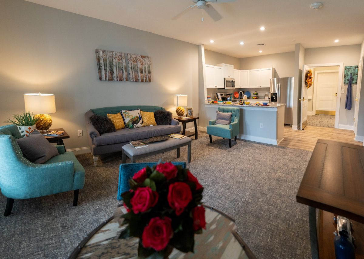 A cozy living room with a view of the kitchen, featuring comfortable seating and stylish decor.
