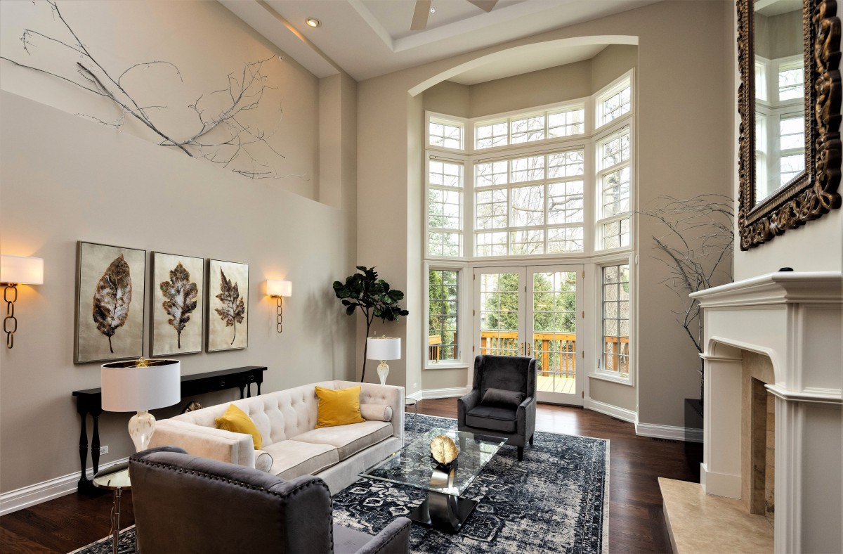 A spacious and elegantly designed living room featuring modern furniture, large windows, and high ceilings.