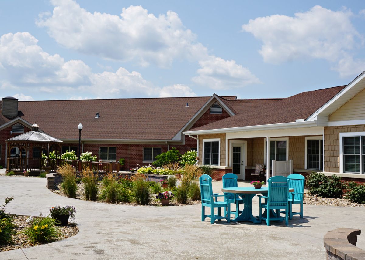 A charming house with a garden patio featuring outdoor seating under a blue sky with clouds.