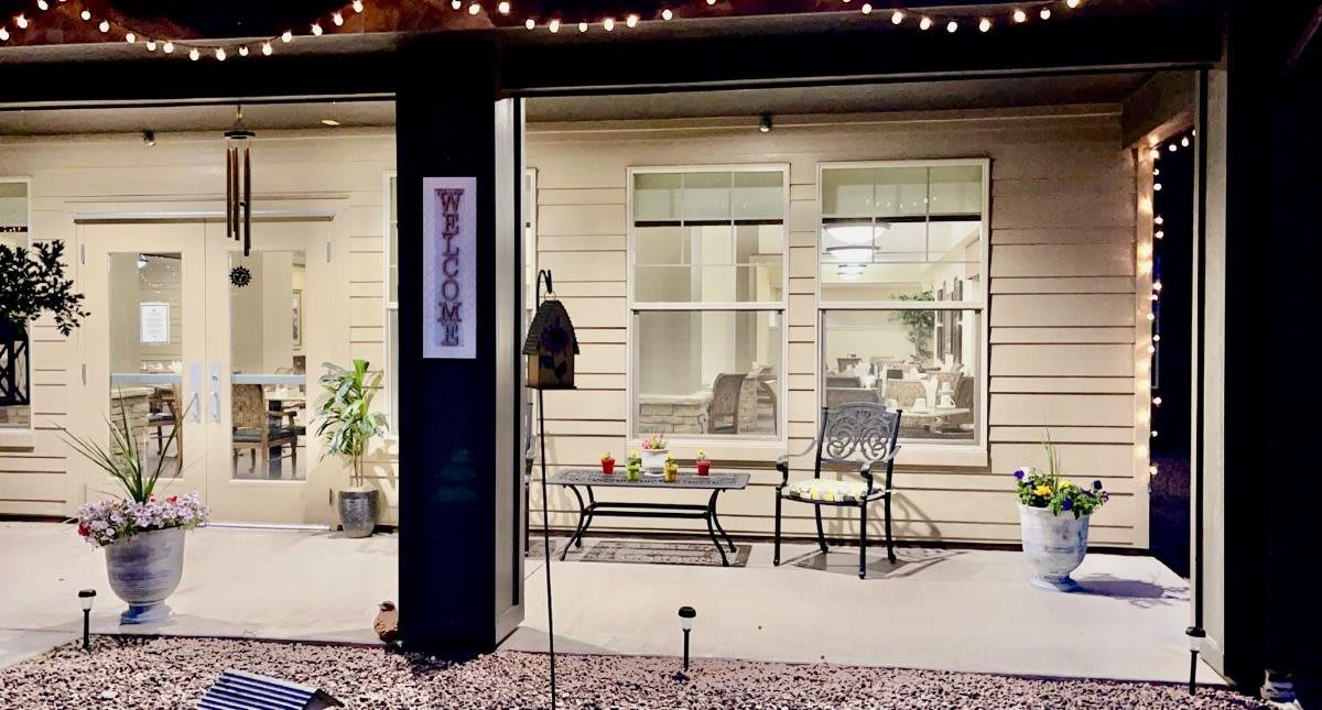 A cozy patio with seating, illuminated by evening lights, featuring a welcome sign.