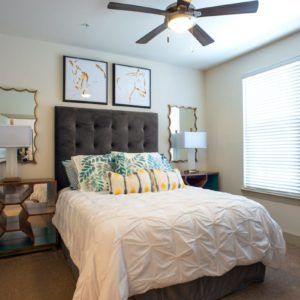 A cozy and stylishly decorated bedroom with a plush bed, decorative pillows, and modern lighting.