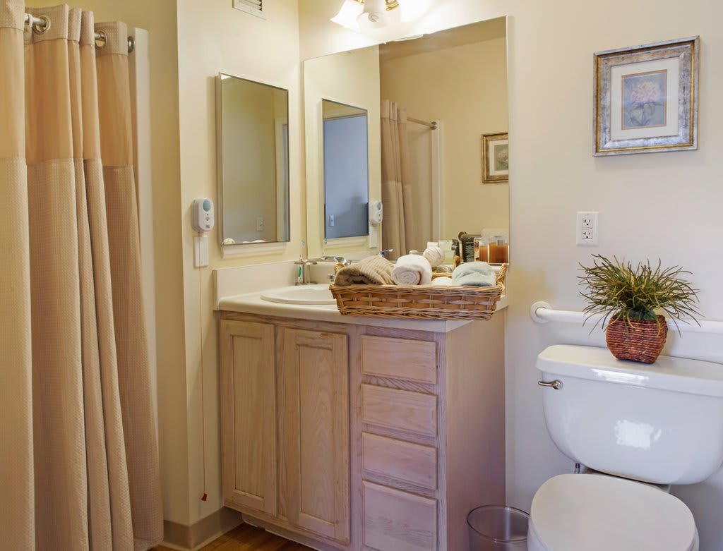A tidy and well-organized bathroom with a vanity, mirror, and shower.