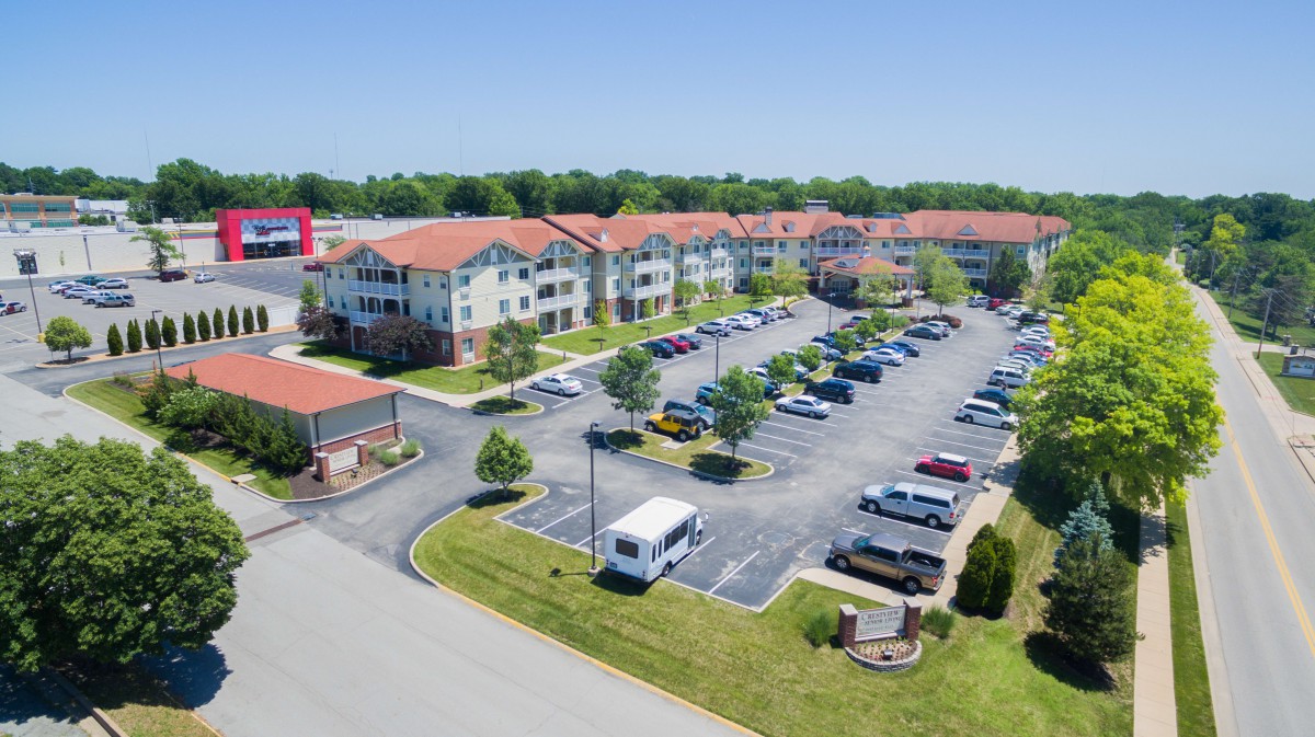 Aerial view of an apartment complex with a parking lot surrounded by greenery.