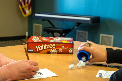 Two players engaged in a game of Yahtzee, rolling dice and keeping score.