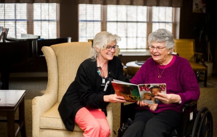 Two women enjoying a magazine together in a cozy indoor setting.