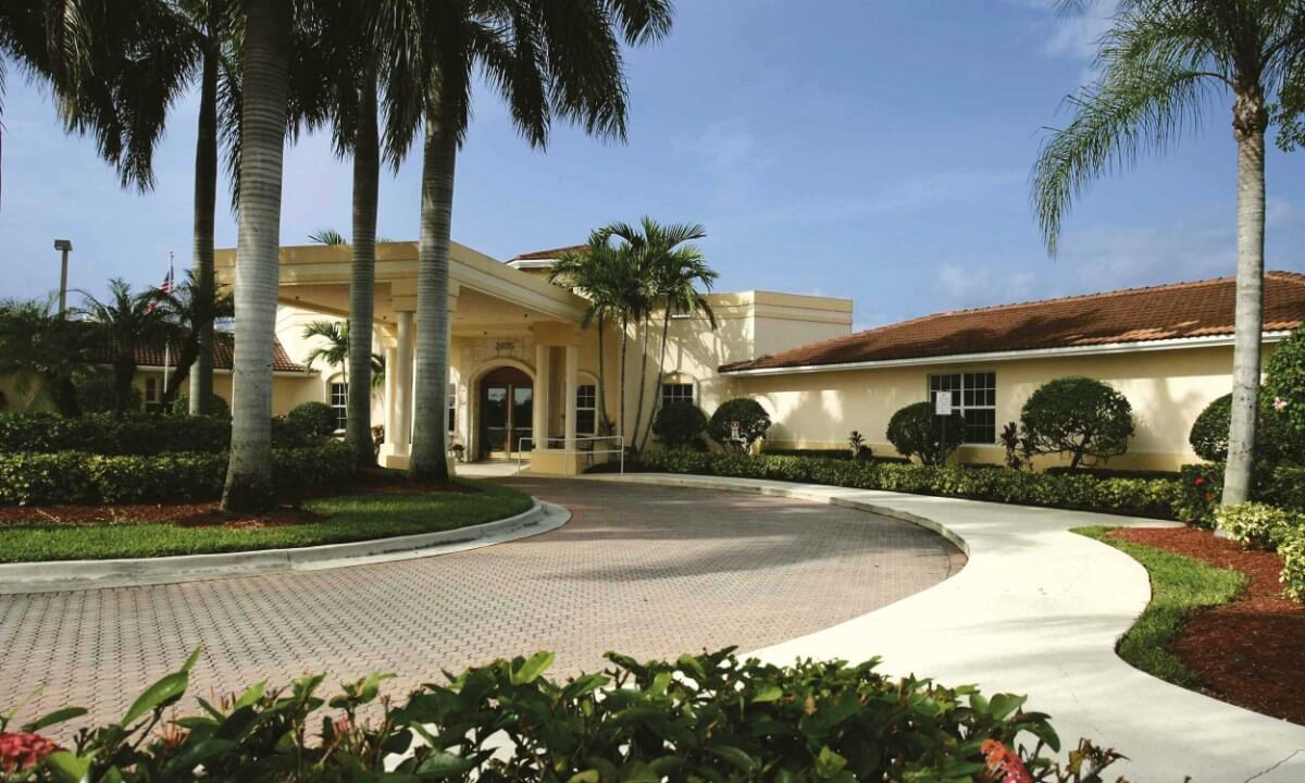A beautiful building with palm trees and a circular driveway.