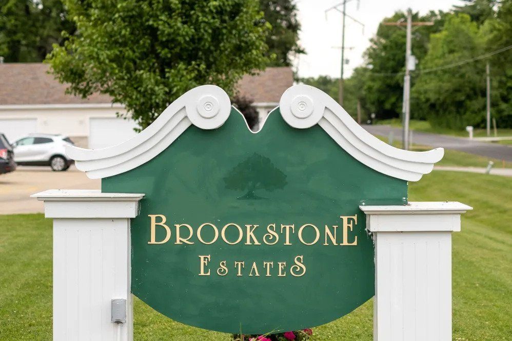 A green sign with white trim for Brookstone Estates, located outdoors.