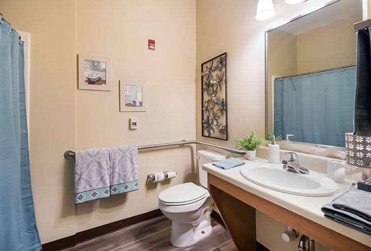 A neatly organized bathroom with a sink, mirror, and decorative elements.