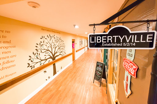 A welcoming hallway featuring a sign for 'Liberty' and a decorative tree mural on the wall.