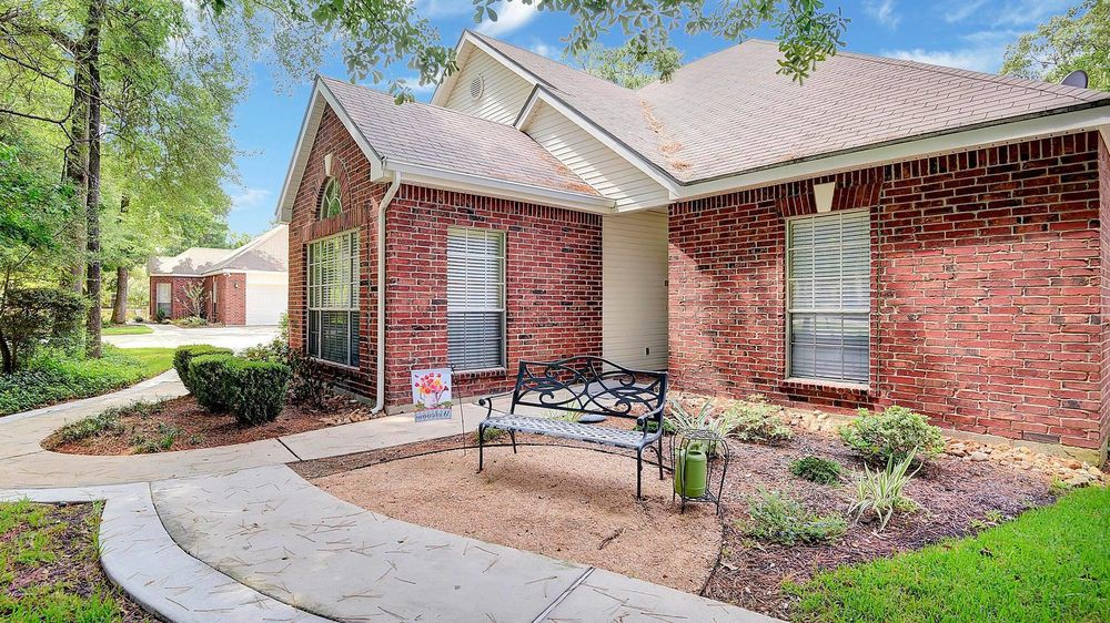 A charming brick house with a small front yard and a bench by the pathway.