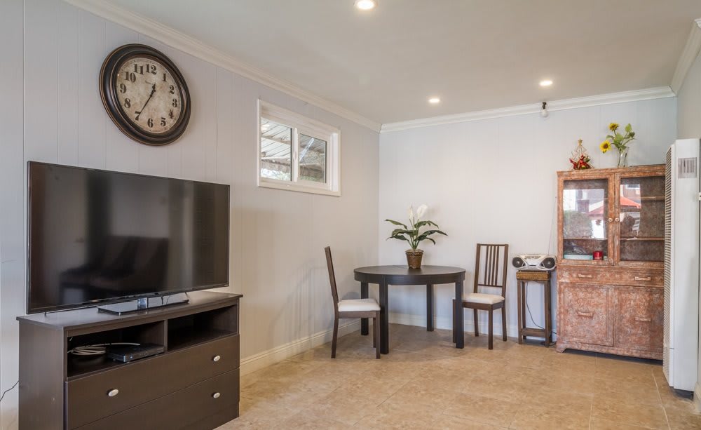 A cozy living room with a television and a small dining table set.