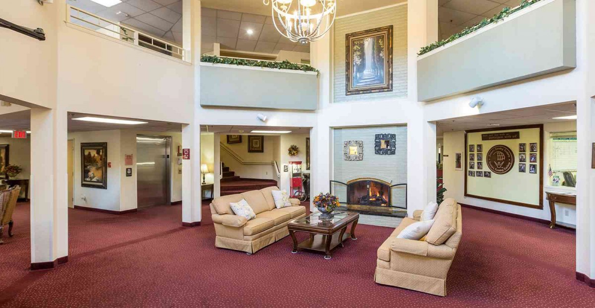 A spacious lobby with comfortable sofas, a central fireplace, and a grand chandelier.