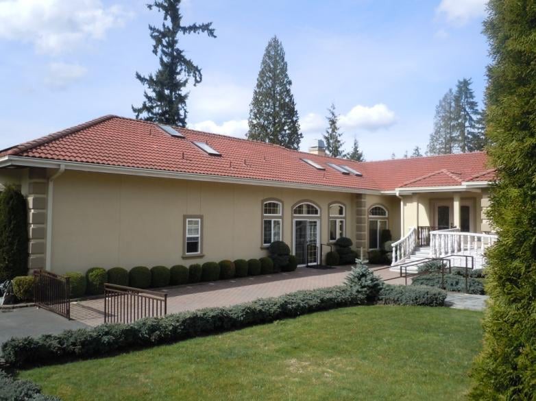 A single-story house with a red roof and landscaped yard.
