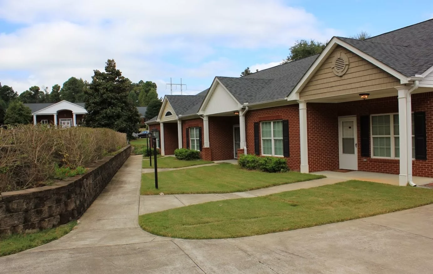 A row of suburban houses with neatly trimmed lawns and a paved sidewalk on a clear day.