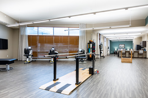 A spacious physical therapy studio featuring exercise equipment and ballet bars for rehabilitation and fitness activities.