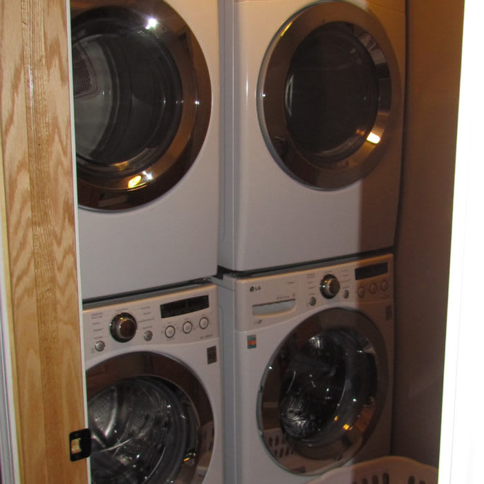 Stacked washers and dryers neatly arranged in a closet.