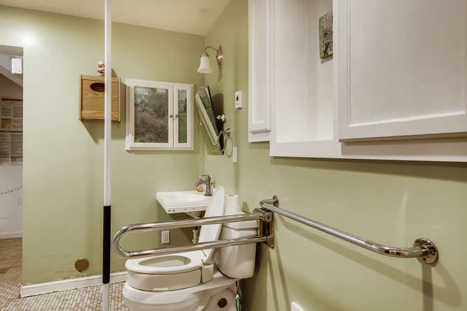 An accessible bathroom with grab bars and green walls.