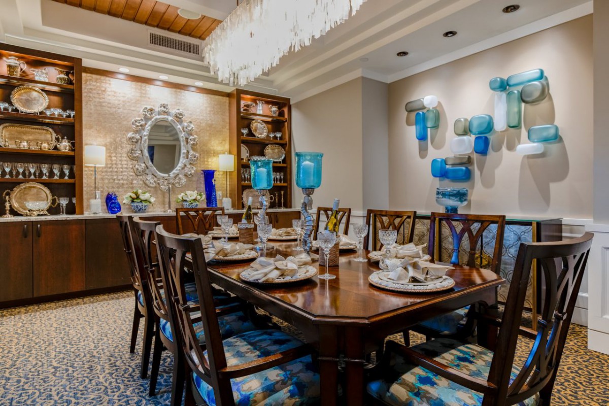 A luxurious dining room with elegant decor, featuring a large wooden table, stylish chairs, and blue accents.