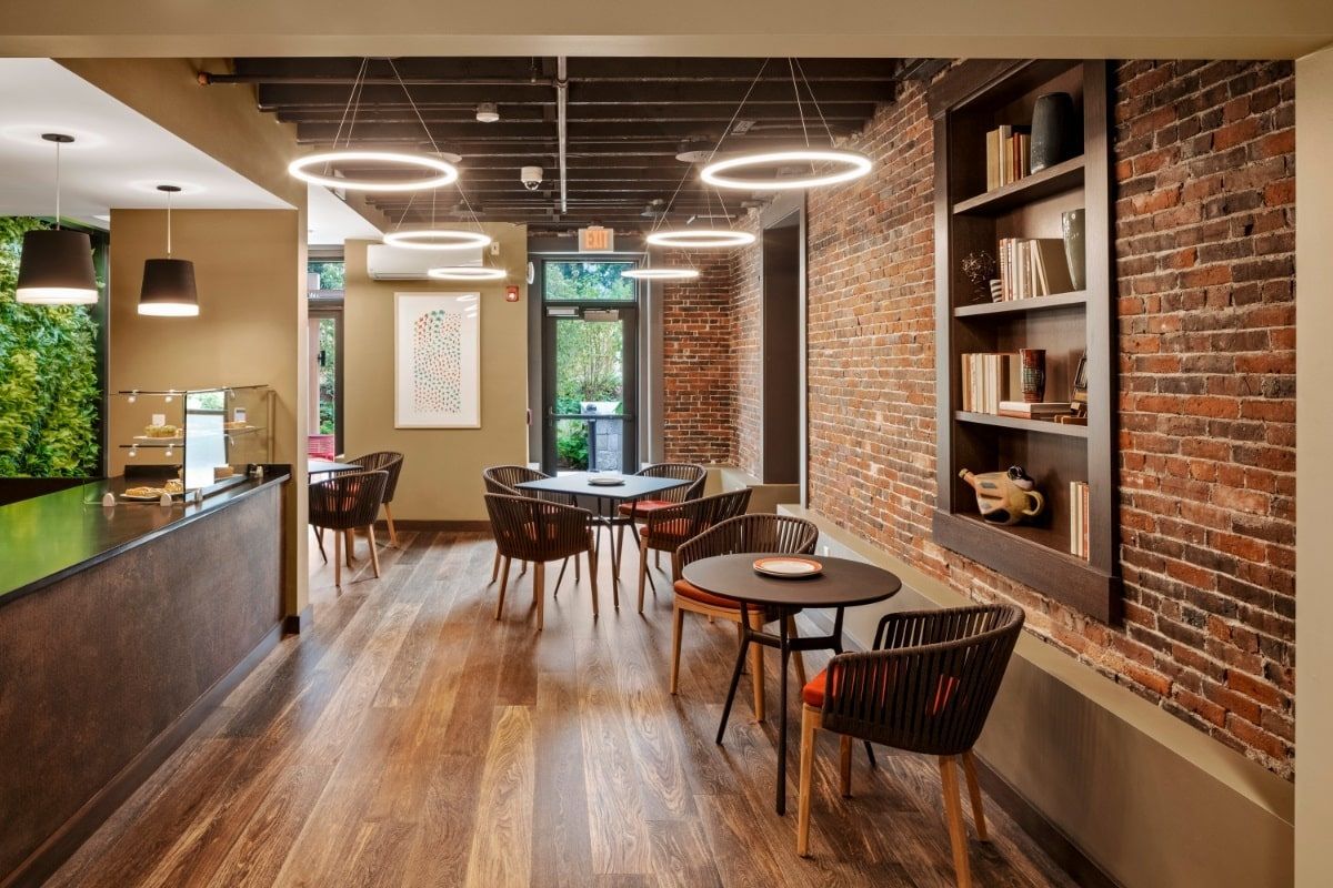 A modern cafe interior with cozy seating, brick walls, and circular lighting.