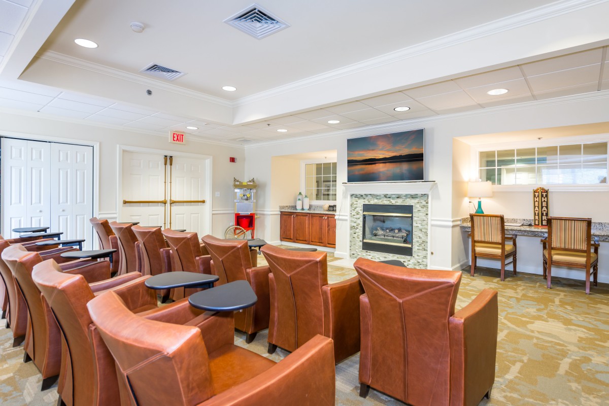 A modern lounge area featuring leather armchairs, a fireplace, and a television.