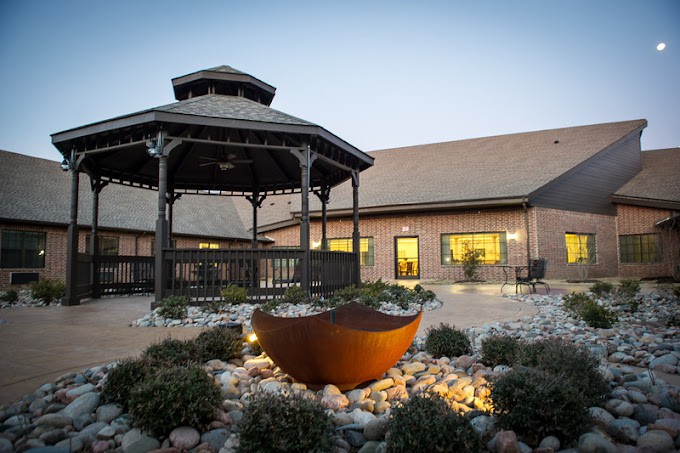 A well-lit gazebo in a garden setting during the evening.