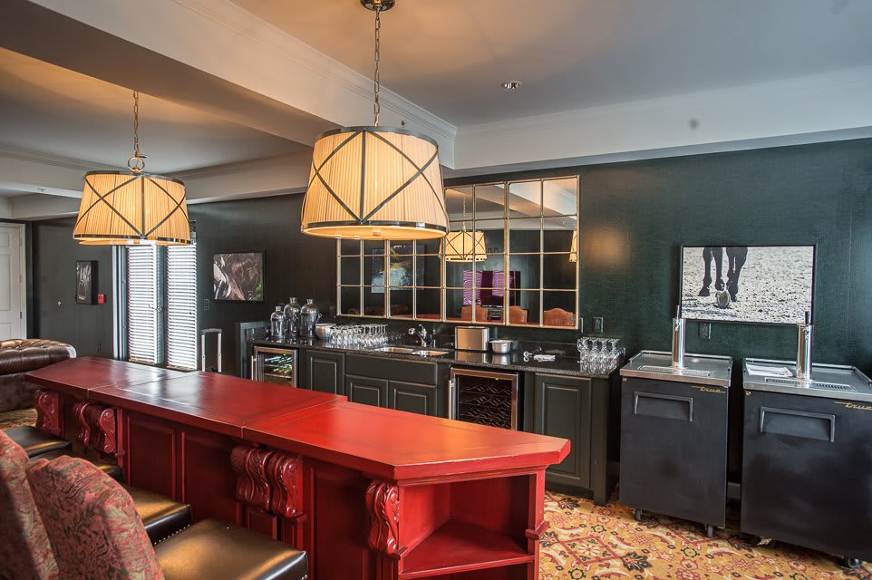 A modern kitchen with a bar area, featuring a red countertop and pendant lighting.