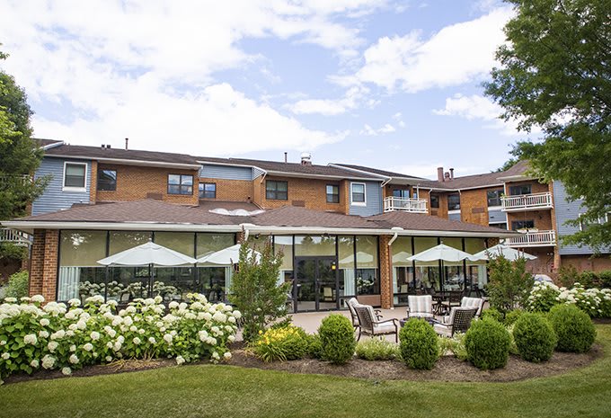 A residential building with a well-maintained garden and outdoor seating area under a partly cloudy sky.