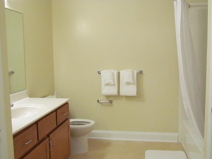 A clean and simple bathroom with a toilet, sink, and towels hanging on the wall.