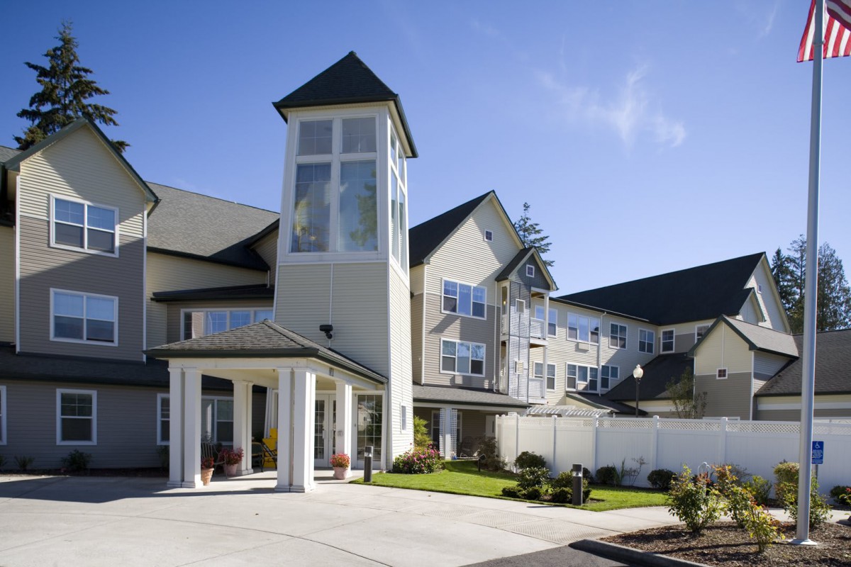 A modern residential building with a prominent tower feature on a sunny day.