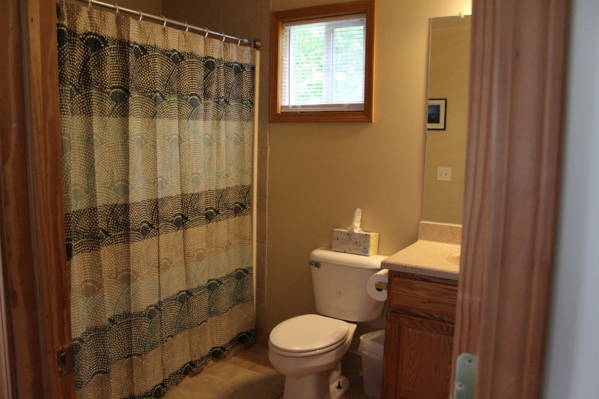 A cozy bathroom featuring a shower curtain, toilet, sink, and window.