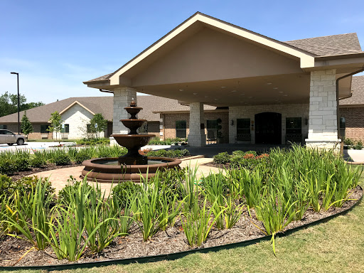 A beautifully landscaped entrance featuring a fountain and well-maintained gardens.