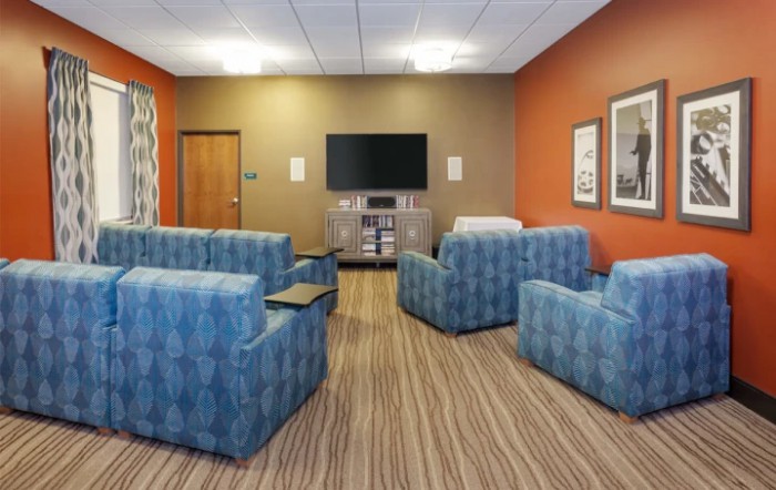 A cozy meeting room with blue couches and a television.