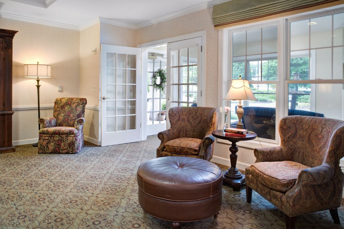 A cozy living room with armchairs, an ottoman, and a warm ambiance.