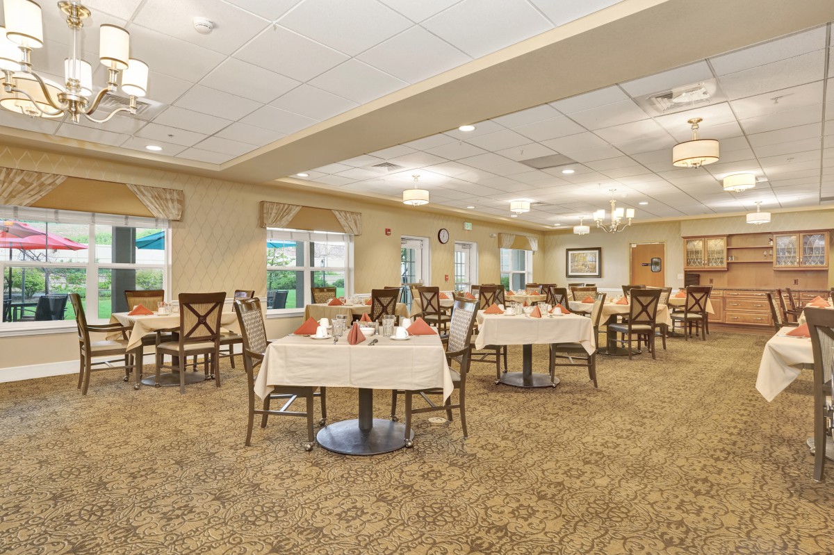 A well-lit dining room with neatly arranged tables and chairs, featuring elegant decor.