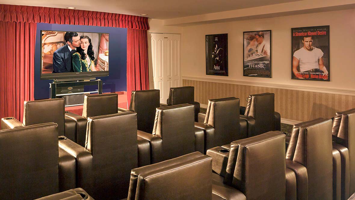 A cozy home theater room featuring luxury seating and classic movie posters on the walls.