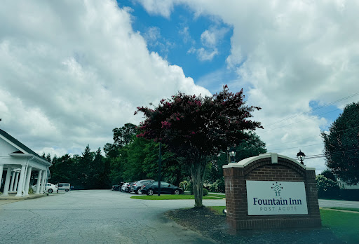Entrance to Fountain Inn surrounded by greenery and a cloudy sky.