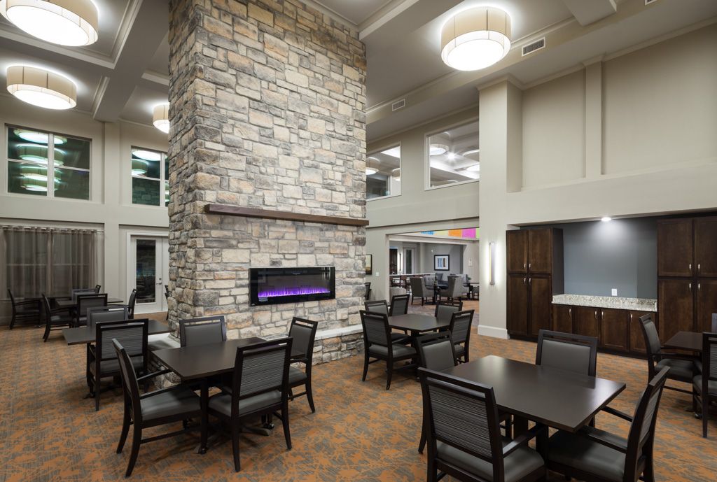 A modern dining area with a central stone fireplace and multiple tables and chairs.