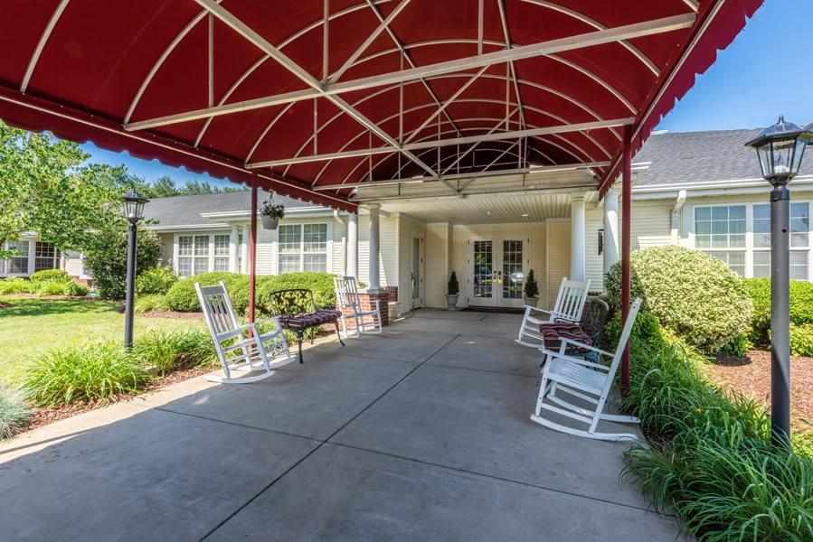 A welcoming entrance with a red awning and rocking chairs.