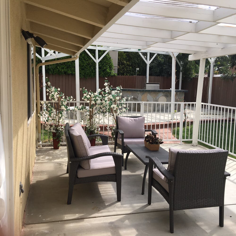 A cozy patio area with comfortable seating and a pergola, overlooking a garden.