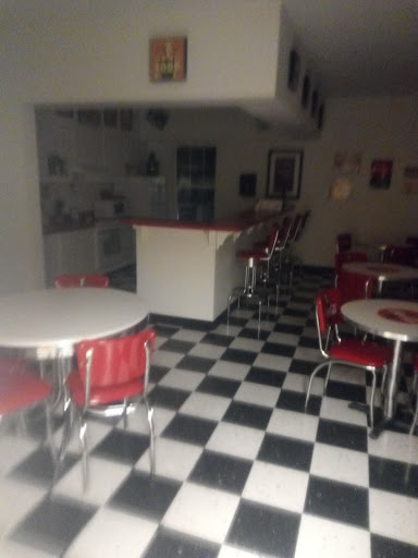 A retro-style diner interior featuring checkered flooring and red seating.