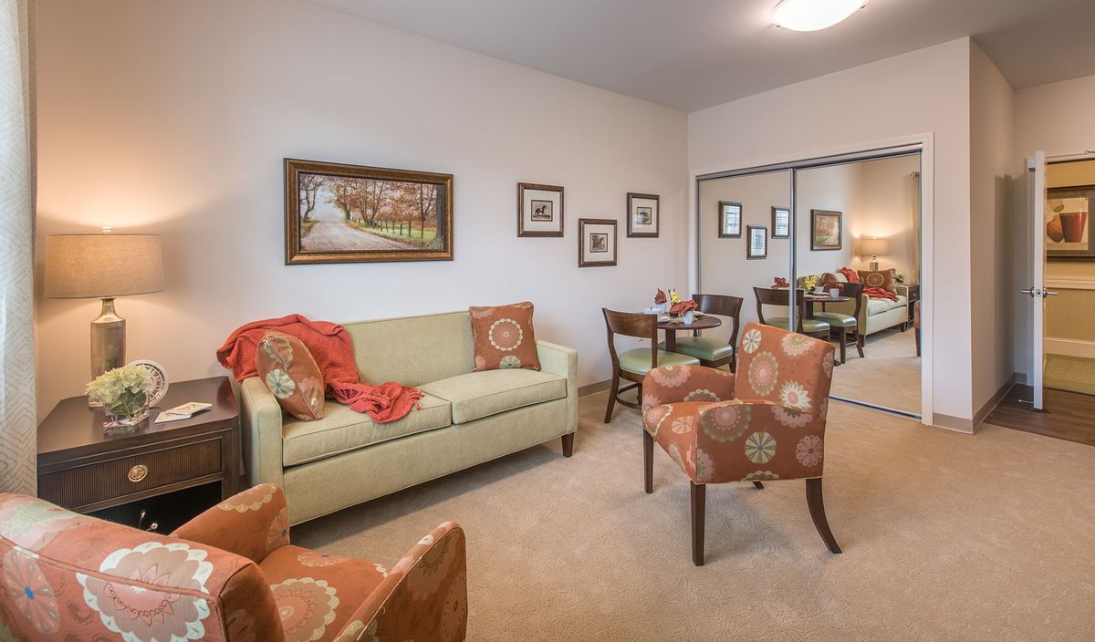 A cozy living room with a sofa, patterned chairs, and decorative artwork on the walls.
