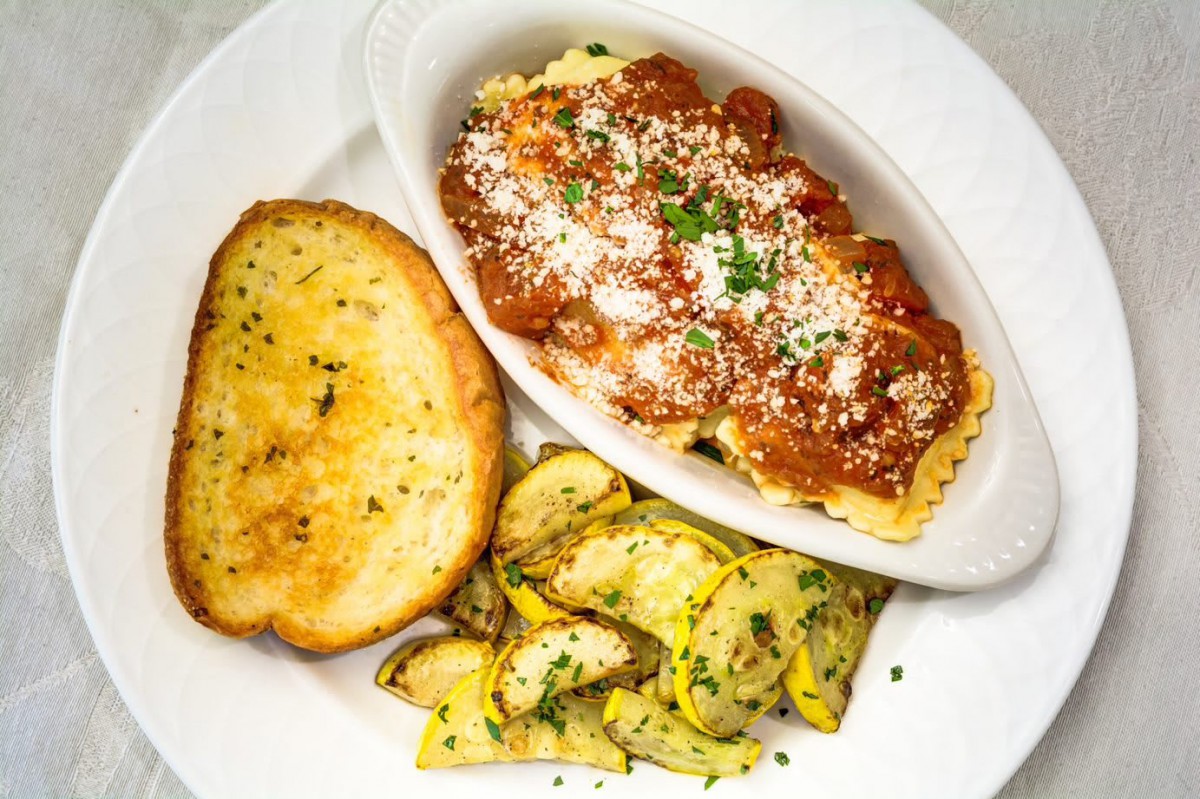 A savory Italian meal featuring pasta with tomato sauce and cheese, accompanied by garlic bread and sauted zucchini.